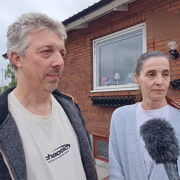Två personer intervjuas med mikrofon utanför ett rött tegelhus i Klippan efter det misstänkta dubbelmordet.