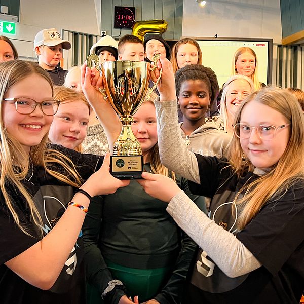 Två femteklassare håller upp en guldpokal framför sin klass och alla ser glada ut.