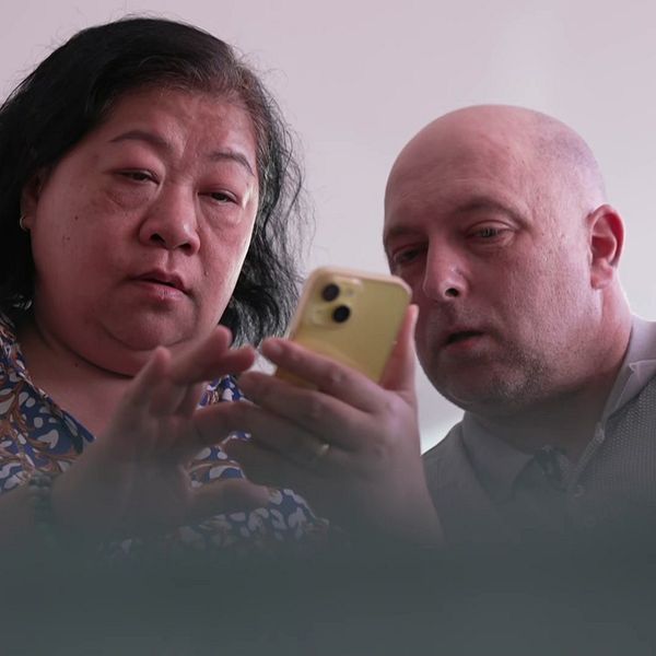 Två personer tittar tillsammans på en mobiltelefon.