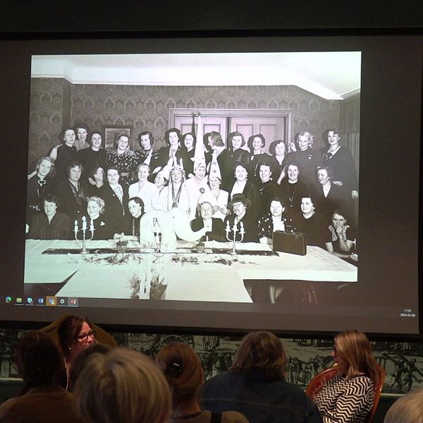 Bild på kvinnor i grupp på storskärm, inne på stadsmuseet