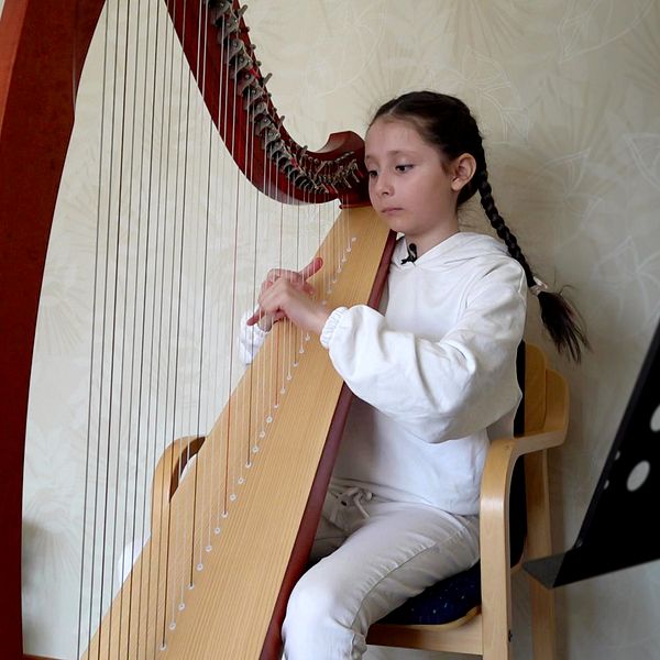 Diana Pyliavska, 9 år, sitter vid sin harpa i bostaden i Luleå.