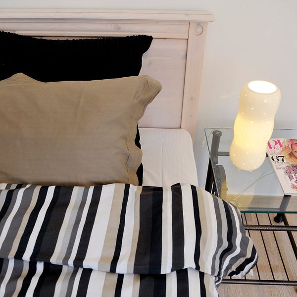 En bäddad säng och ett soffbord syns i en lägenhet.