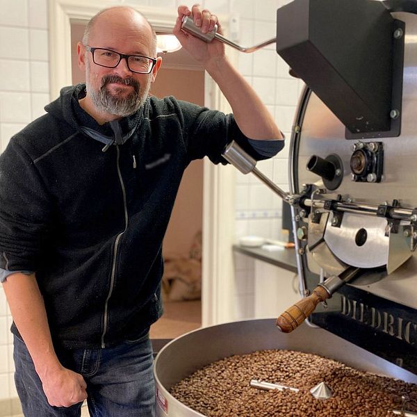 Person rostar kaffebönor i en stor rostningsmaskin.