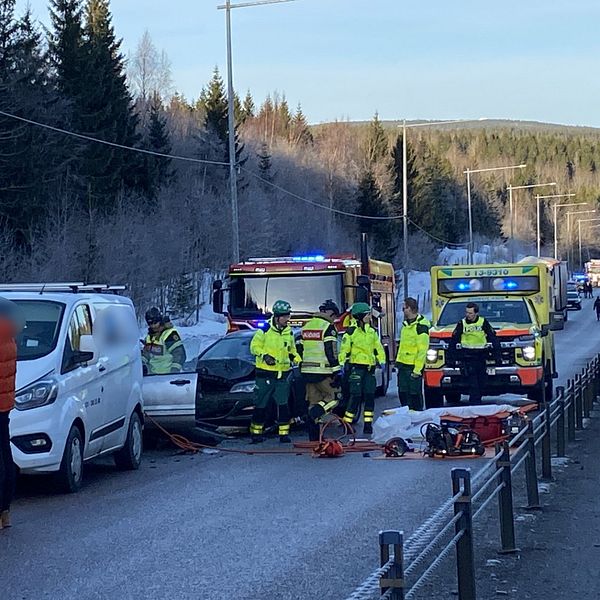 Räddningspersonal arbetar vid en olycksplats med flera ambulanser på en vinterväg.