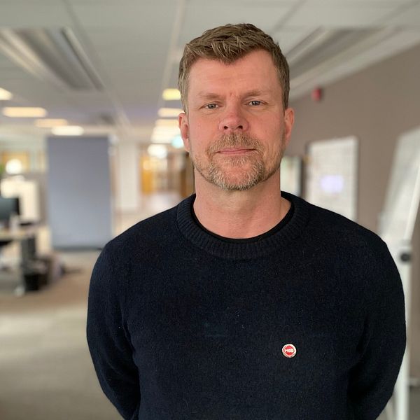 Petter Säterhed, funktionsansvarig på MSB, i svart tröja står i ett kontorslandskap med skrivbord och datorskärmar i bakgrunden.
