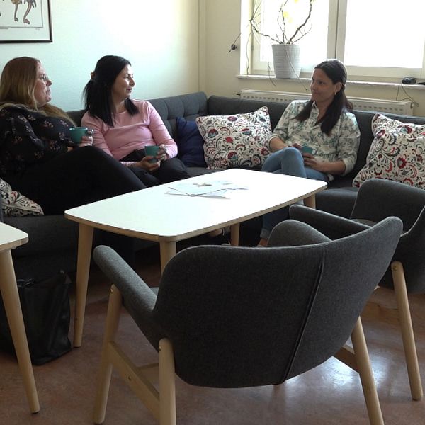 Tre kvinnor sitter och samtalar i en soffa