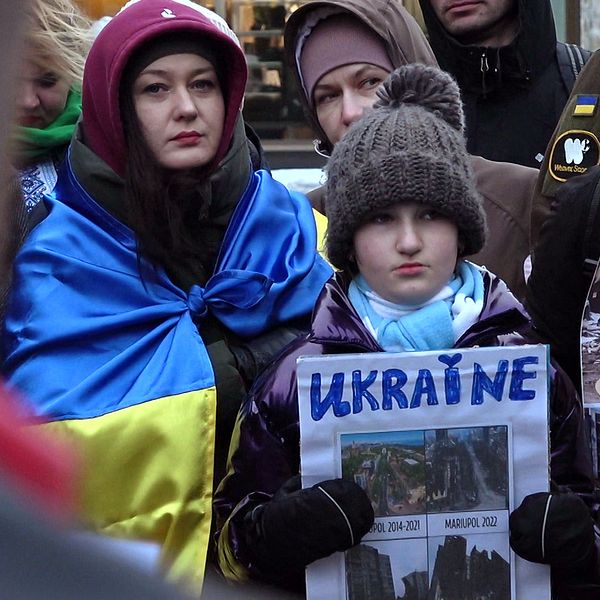 en kvinna och ett barn som håller ett Ukraina-plakat i en folkmassa vid manifestation i Luleå