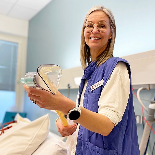 kvinna står i förlossningssal och visar en lustgas andningsmask