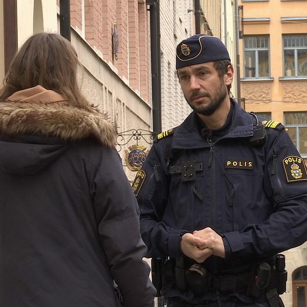 Polis står och pratar med en reporter på en gata.