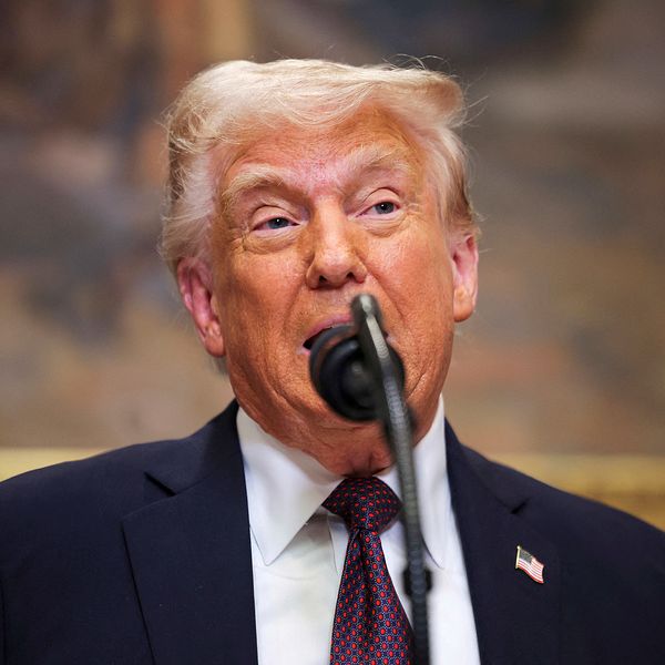 Donald Trump står framför mikrofon, rygg mot konstverk i guldram.
