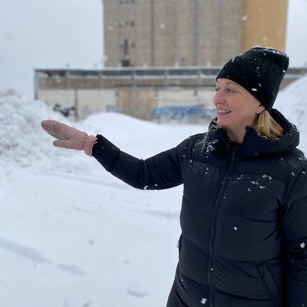 Kvinna står i snöyra och vevar med sin hand.