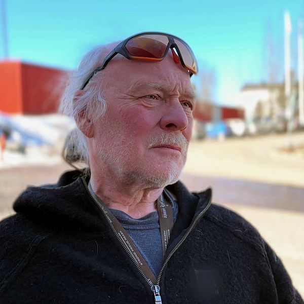 Matti Blind Berg utomhus i vintermiljö framför röda byggnader.