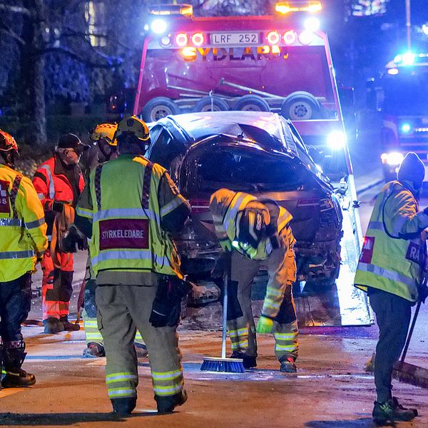 Räddningspersonal i varselklädsel på gata genom Brösarp i Tomelilla kommun, där en förstörd bil bärgas efter en allvarlig trafikolycka