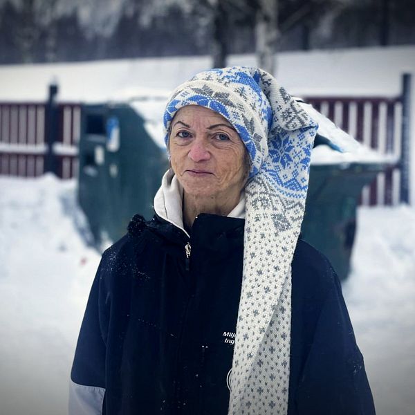 Inger Olofsson står framför gröna containrar på en återvinningsstation i Vännäs