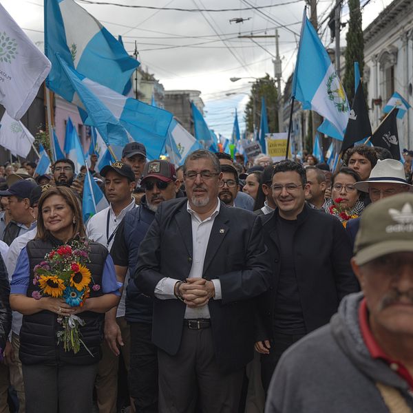 Vinnaren i presidentvalet Bernardo Arévalo omgiven av demonstranter med glada ansikten och guatemalanska flaggor.