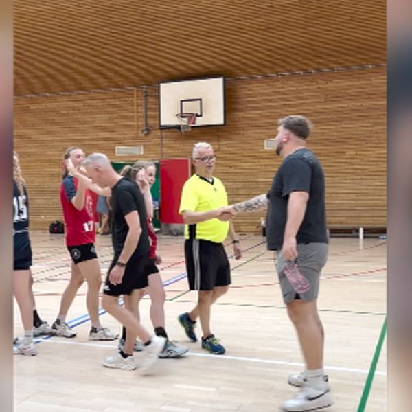 Jan Holm i gul domartröja på handbollsplanen med spelare.