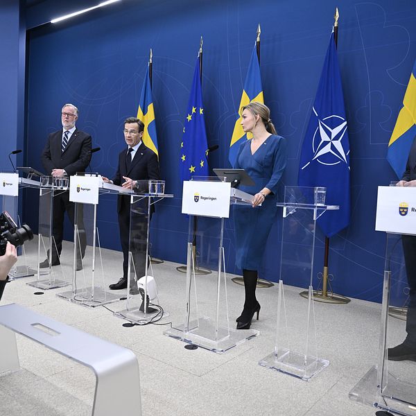 Presskonferens med svenska politiker framför EU och Nato-flaggor. Fotograf på plats.