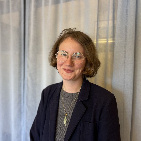 Irja Nilsson Nyberg står framför ljusgrå gardiner.