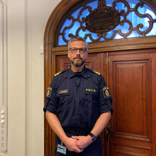 Polisen Johan Höglund som står framför en stor dörr i sin polisuniform.