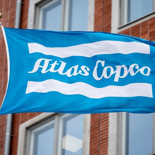 En flagga med Atlas Copcos logga på utanför en byggnad.