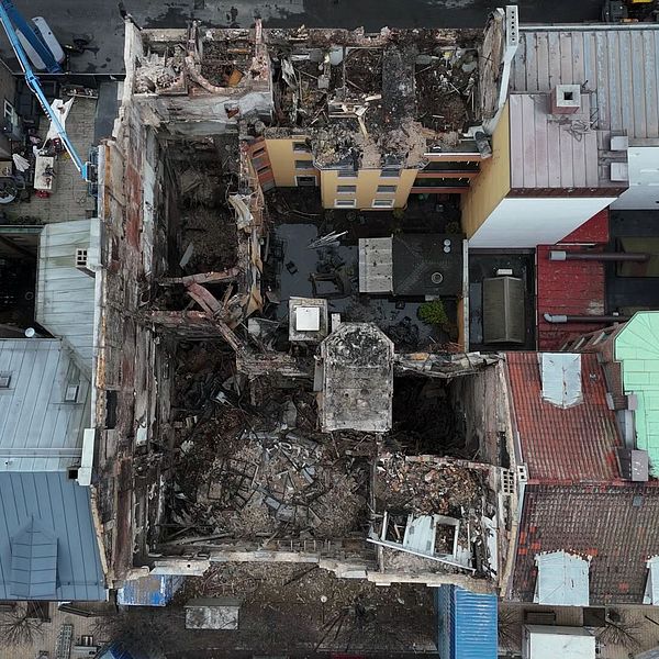 Översiktsbild av det ödelagda Hotell Kärnan i Helsingborg. Byggnaden är omgiven av intakta hus, vilket visar ruinerna av det kollapsade taket och den förstörda interiören efter branden.