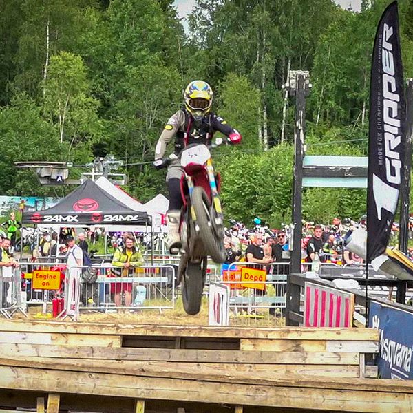 En enduromotorcykel flyger över ett hopp med publik.