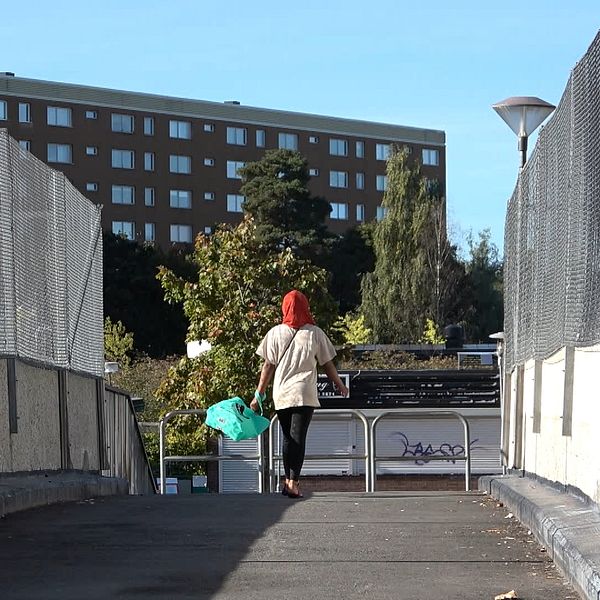 en flicka i hijab går på en bro, i bakgrunden ett höghus