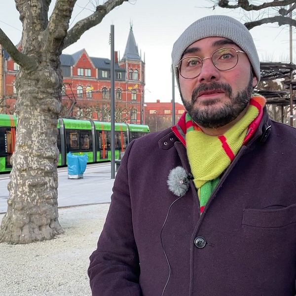 Saman Tondnevis, affärsområdeschef buss och spårvagn på Skånetrafiken, står framför en spårvagn på hållplatsen på Clemenstorget i Lund.
