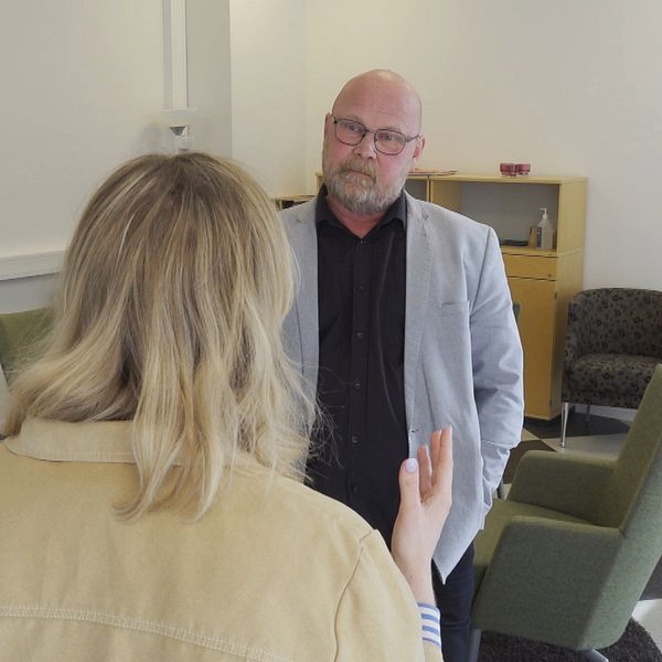 En kvinna står med ryggen mot kameran och pratar med en man. De står i ett konferensrum.