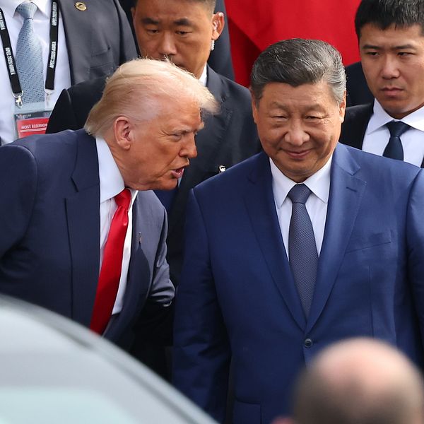 Donald Trump och Xi Jinping möts omgivna av säkerhetspersonal vid ett officiellt evenemang.