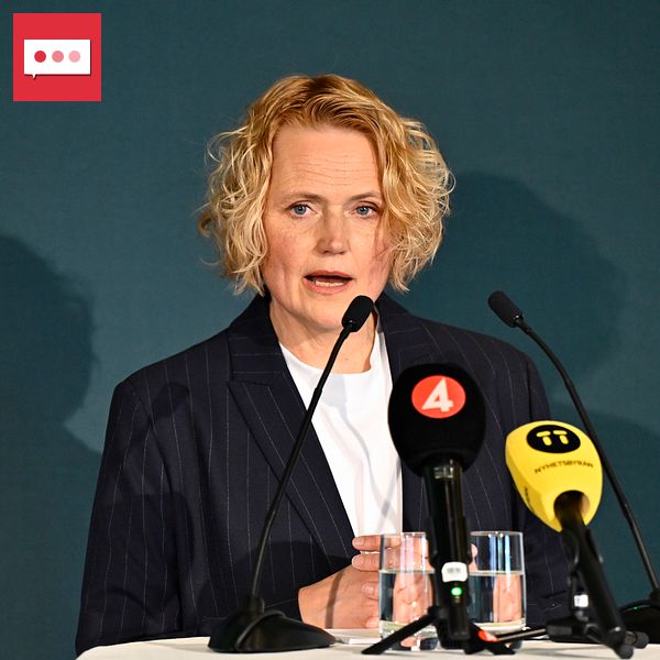Person vid talarstol med mikrofoner och tv-mikrofoner från TV4 och SVT framför sig.