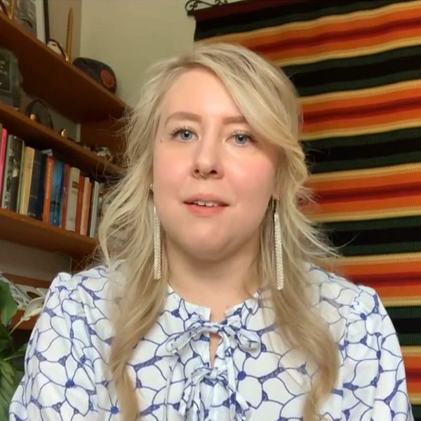 Sanna Laakso i hemmet framför en färgstark väggbonad
