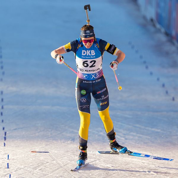 En skidskytt tävlar i en individuell distans, nummer 62, i full fart på snöspåret.