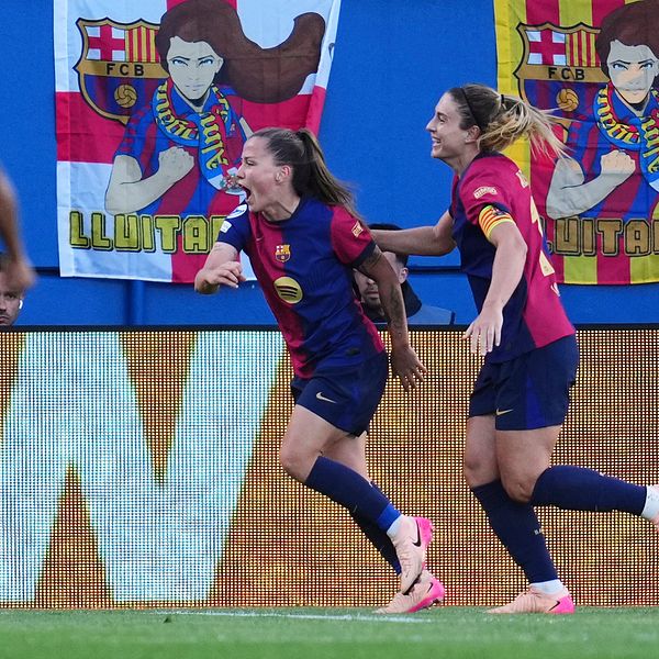 Fotbollsspelare i Barcelona firar mål framför flaggor på läktaren.