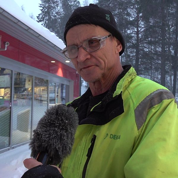 Man i gul jacka utanför bensinstation.