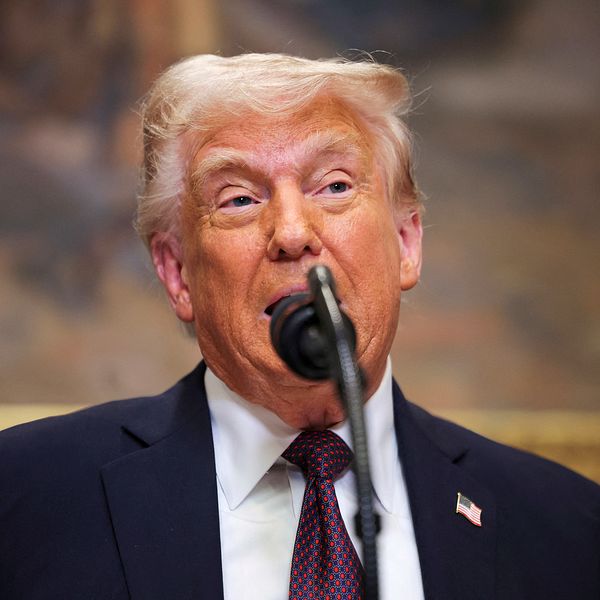 Donald Trump står framför mikrofon, rygg mot konstverk i guldram.