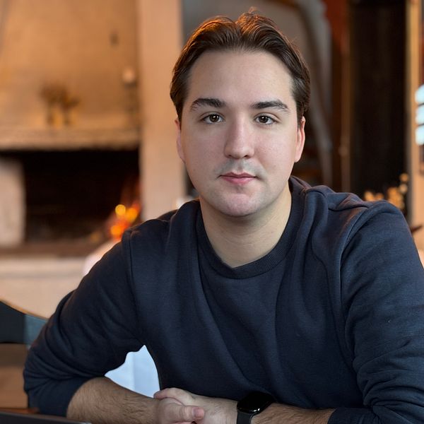 Thomas Lönnberg i Duved tittar in i kameran i en hemmamiljö med öppen spis i bakgrunden.