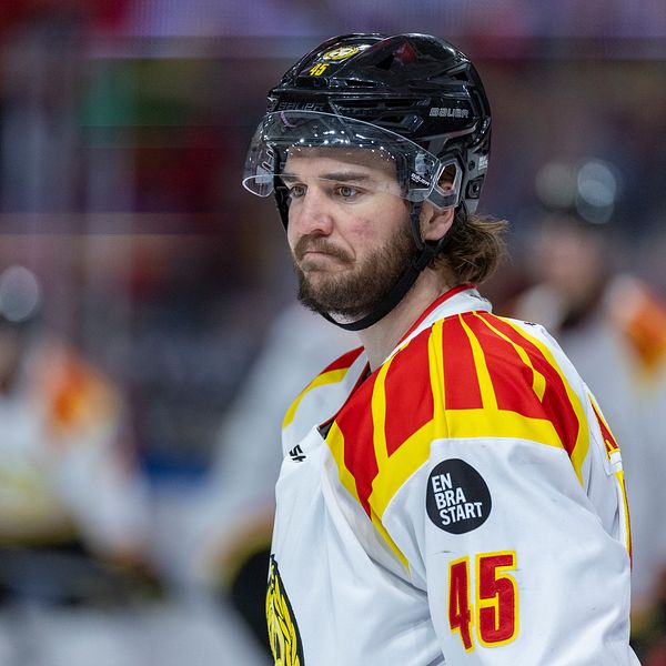 Ishockeyspelare i vit tröja med rödgula ränder och nummer 45 på isen under match.