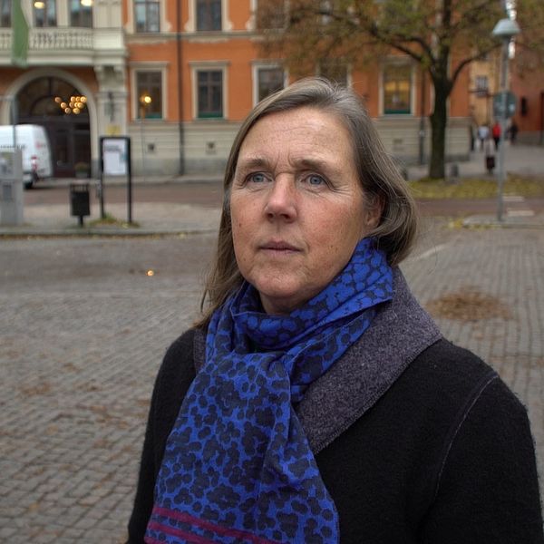 Kvinna med blå halsduk på torg med parkering