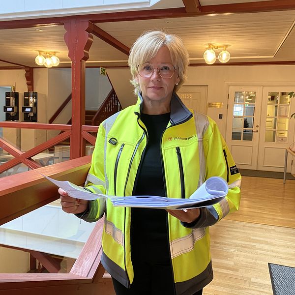 En kvinna står med papper i handen
