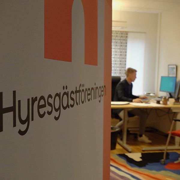 En bild på en skylt från Hyresgästföreningen och ett kontor i bakgrunden där Hasse Dahl sitter och arbetar i Östersund.