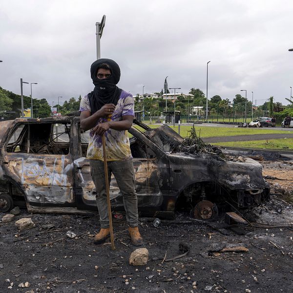 En man står framför en utbränd bil