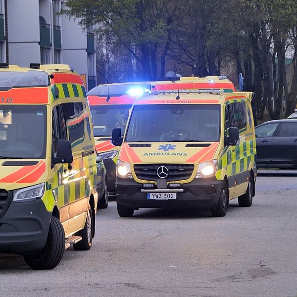 Två ambulansfordon parkerade vid en väg, ett med blinkande blåljus.