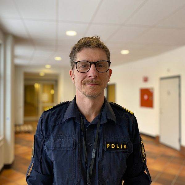 Johan Sangby, polis. Han har uniform på sig och står i en korridor.
