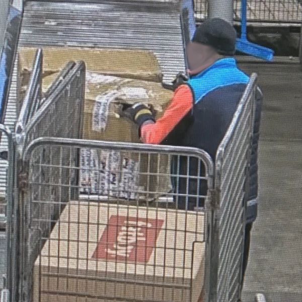 En lagerarbetare hanterar paket vid ett transportband i en industrilokal.