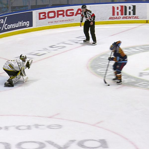 Ishockeyspelare skjuter straff mot målvakt, domare följer spelet på isen.