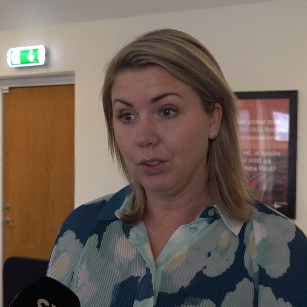 På bilden syns en blond kvinna med halvlångt blont hår och en blå blommig blus.