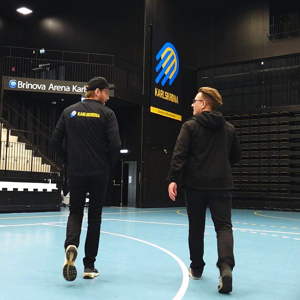 HF Karlskronas klubbchef Olof Ljungberg och reporter Henrik Friberg går på en tom handbollsplan i Brinova arena.
