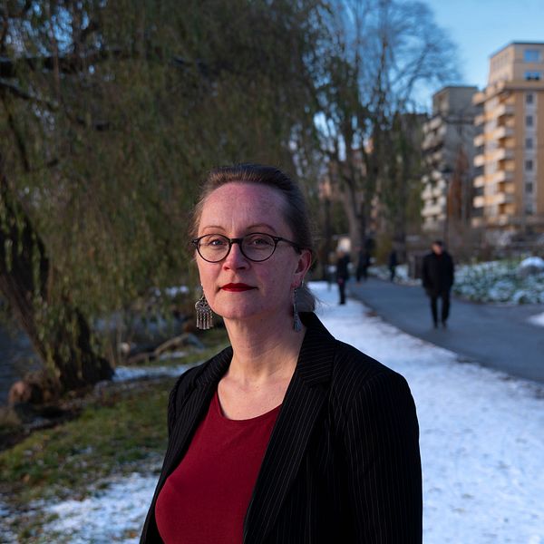 Niki Bergman utomhus vid en gångväg med snö och bostadshus i bakgrunden.