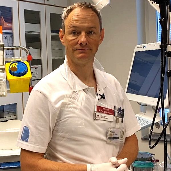 Gert Nestler, chef på kirurgkliniken i Falun, iklädd vita arbetskläder, sitter bland sjukvårdsutrustning.